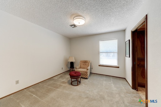 unfurnished room featuring a textured ceiling and light carpet