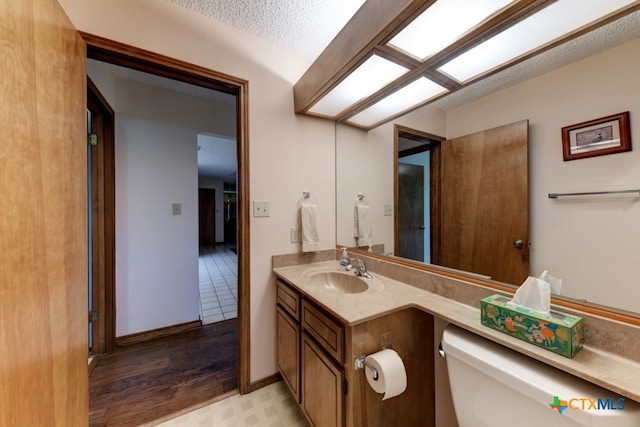 bathroom featuring a textured ceiling, vanity, hardwood / wood-style flooring, and toilet