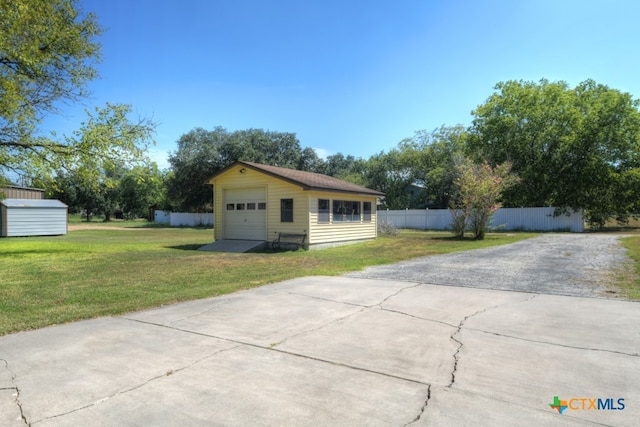 view of front facade featuring a garage, a front yard, and an outdoor structure