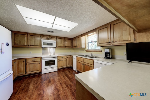 kitchen with dark wood-type flooring, white appliances, sink, and a textured ceiling