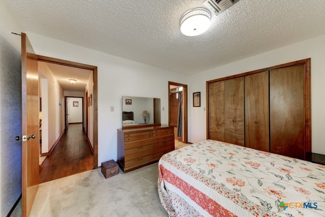 bedroom with a closet, a textured ceiling, and light hardwood / wood-style flooring