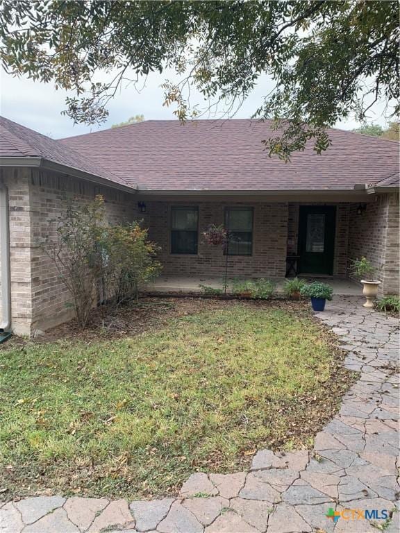 single story home with brick siding, roof with shingles, and a front yard