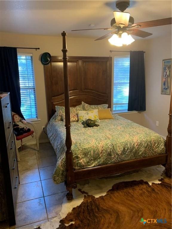 bedroom with light tile patterned floors, a ceiling fan, and baseboards