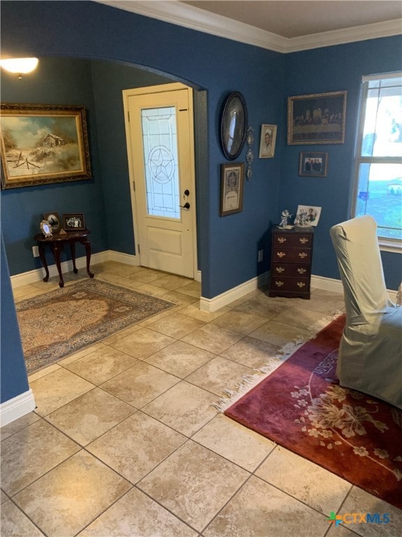 tiled entrance foyer featuring baseboards, arched walkways, and crown molding