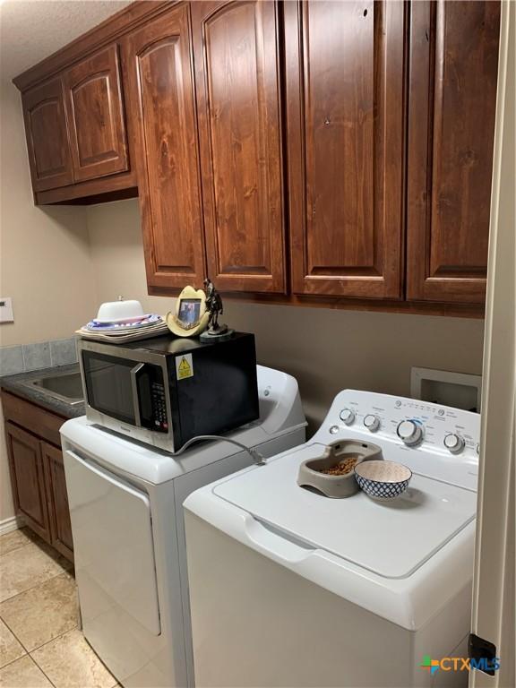 laundry room with cabinet space, light tile patterned floors, and separate washer and dryer