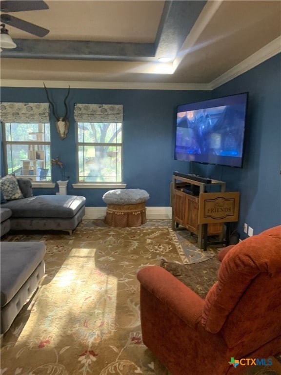 living room with ornamental molding, baseboards, and a ceiling fan