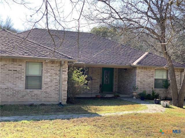 ranch-style home featuring roof with shingles, a front lawn, and brick siding