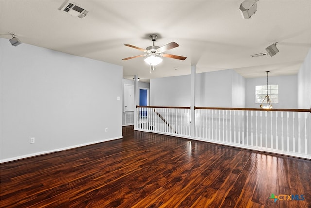 unfurnished room featuring ceiling fan with notable chandelier and dark hardwood / wood-style floors