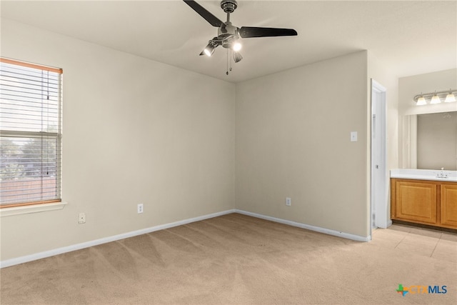 empty room with ceiling fan, sink, and light colored carpet