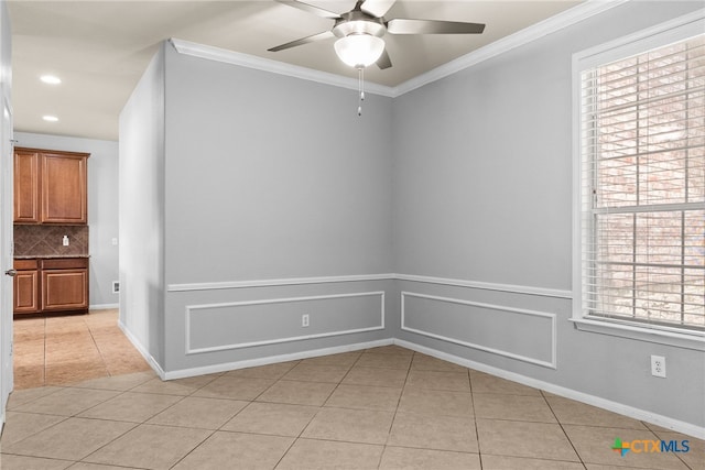 tiled empty room with ceiling fan, plenty of natural light, and ornamental molding