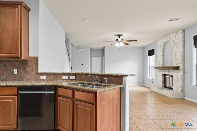 kitchen featuring dishwasher, a stone fireplace, sink, ceiling fan, and light tile patterned flooring