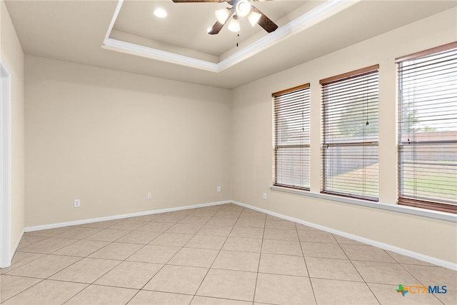 unfurnished room with light tile patterned floors, a raised ceiling, ceiling fan, and a healthy amount of sunlight