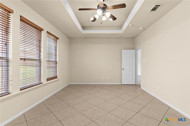 spare room with a tray ceiling, a wealth of natural light, ceiling fan, and light tile patterned floors