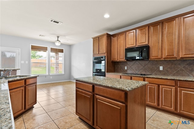 kitchen with light stone countertops, light tile patterned floors, sink, and black appliances