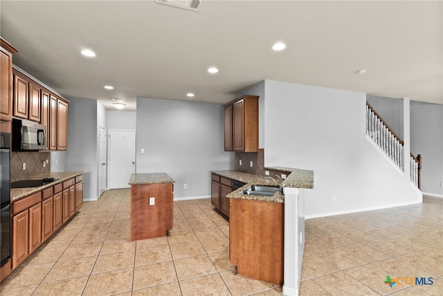 kitchen featuring decorative backsplash, a kitchen island, light tile patterned floors, and sink