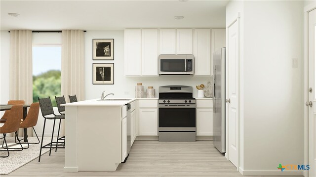kitchen with a peninsula, stainless steel appliances, white cabinetry, a sink, and light wood-style floors
