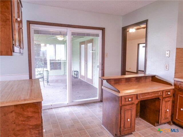 interior space featuring a ceiling fan, brown cabinets, and butcher block countertops