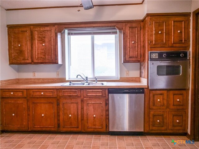 kitchen with a sink, light countertops, stainless steel appliances, and brown cabinets