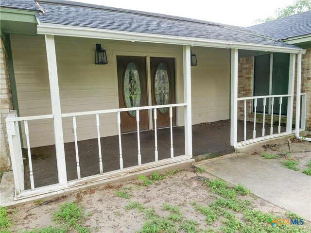 property entrance featuring a porch and roof with shingles