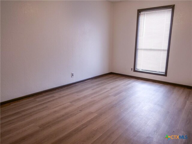 empty room with baseboards and wood finished floors