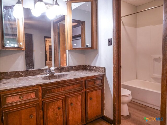 full bath featuring vanity, toilet, wood finished floors, and  shower combination