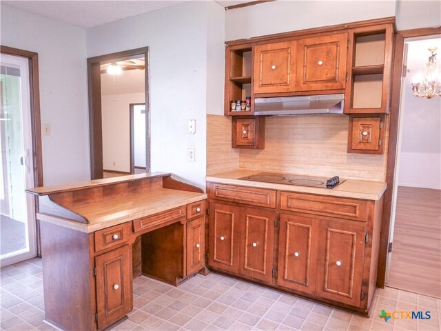 kitchen with brown cabinets, open shelves, black electric stovetop, backsplash, and under cabinet range hood