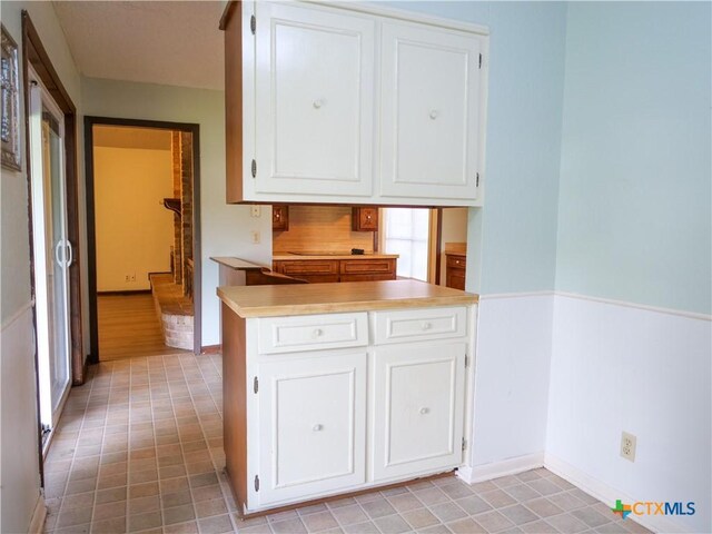 kitchen with baseboards, light countertops, and white cabinetry
