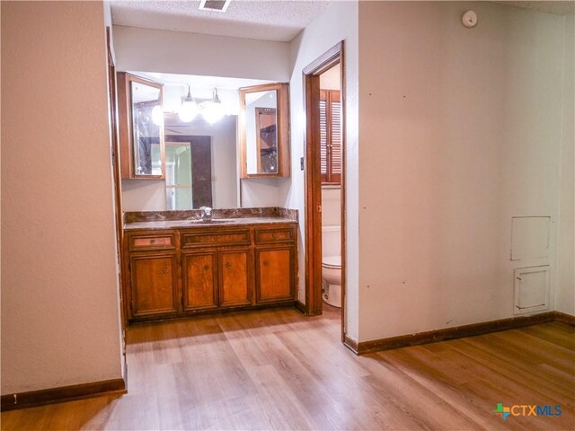 bathroom featuring baseboards, wood finished floors, and toilet