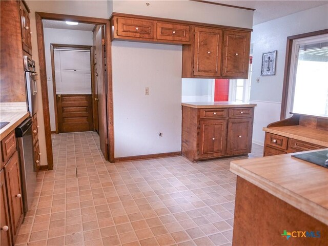 kitchen featuring brown cabinets, light tile patterned flooring, appliances with stainless steel finishes, light countertops, and baseboards