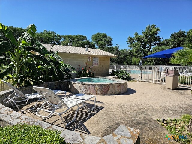 view of pool featuring a patio and an in ground hot tub