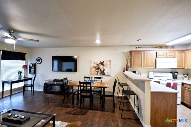 kitchen featuring light brown cabinets, kitchen peninsula, dark wood-type flooring, and white appliances