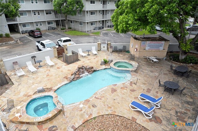 view of pool with a community hot tub, pool water feature, and a patio area