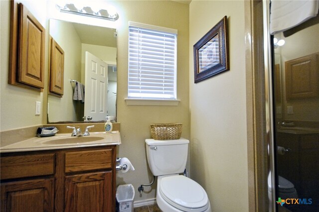 bathroom featuring toilet, vanity, and a shower with door