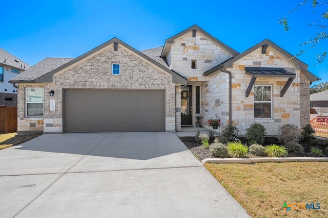 french country home with fence, an attached garage, a shingled roof, concrete driveway, and stone siding