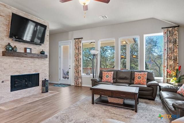 living area with visible vents, wood finished floors, a fireplace, baseboards, and ceiling fan