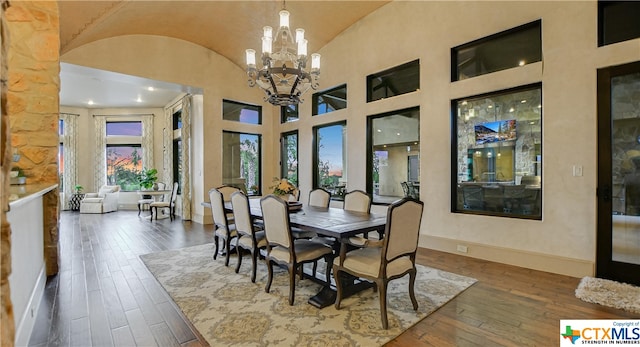 dining space featuring high vaulted ceiling, dark wood-type flooring, and an inviting chandelier