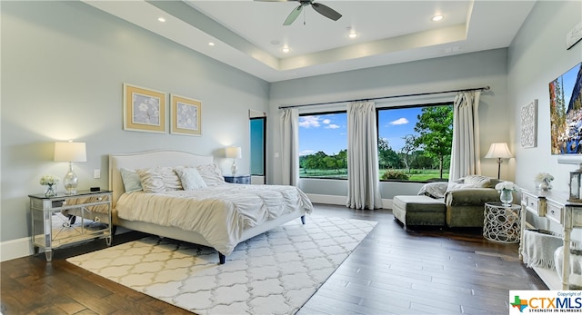 bedroom with hardwood / wood-style flooring, ceiling fan, and a tray ceiling