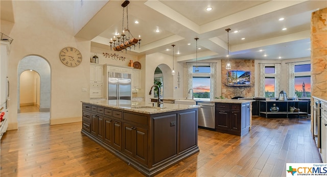 kitchen featuring appliances with stainless steel finishes, dark brown cabinetry, sink, and an island with sink