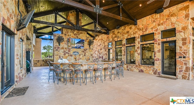 view of patio with an outdoor bar, water heater, and ceiling fan