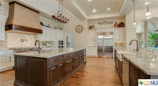 kitchen featuring a spacious island, custom range hood, dark brown cabinets, and stainless steel appliances