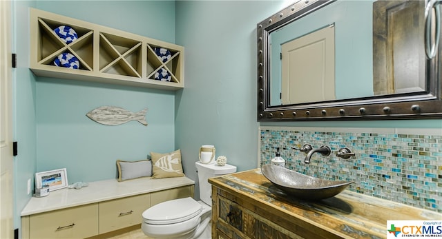 bathroom featuring vanity, toilet, and backsplash