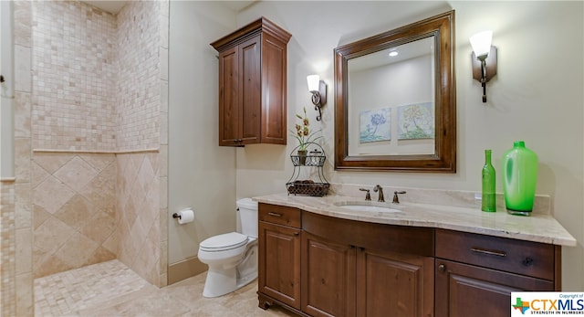 bathroom with tile patterned flooring, vanity, toilet, and a tile shower