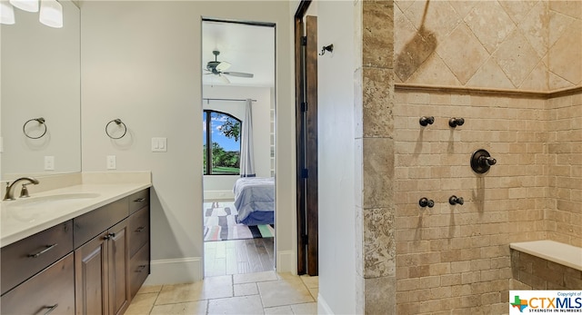 bathroom with hardwood / wood-style floors, vanity, ceiling fan, and a tile shower