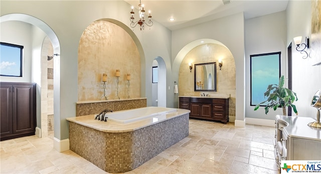 bathroom featuring a high ceiling, vanity, an inviting chandelier, and separate shower and tub