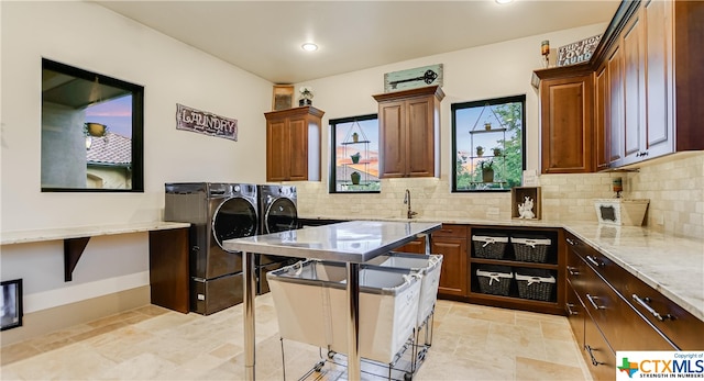 kitchen featuring a breakfast bar area, tasteful backsplash, a kitchen island, light stone countertops, and washer and dryer