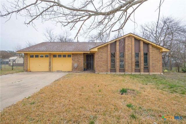 view of front of property featuring an attached garage, a front yard, concrete driveway, and brick siding