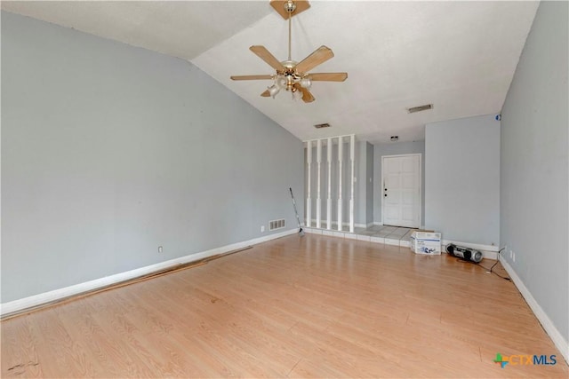 unfurnished room with light wood-style floors, baseboards, visible vents, and vaulted ceiling