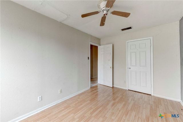 unfurnished bedroom with light wood-style flooring, a ceiling fan, visible vents, and baseboards