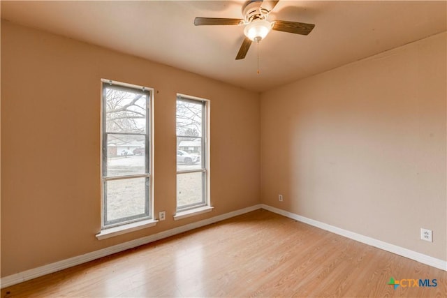 spare room featuring light wood finished floors, ceiling fan, and baseboards