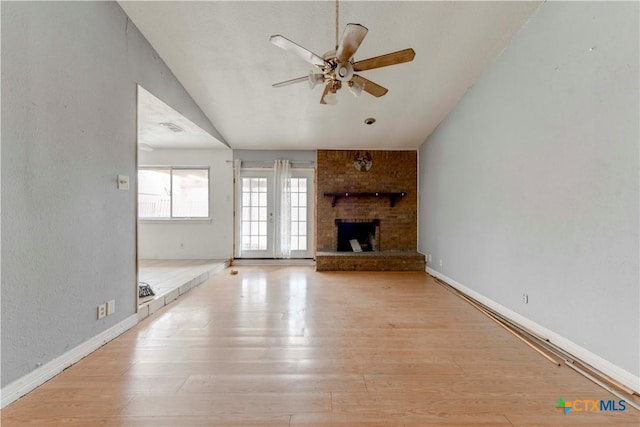 unfurnished living room with lofted ceiling, light wood-style flooring, a fireplace, a ceiling fan, and baseboards